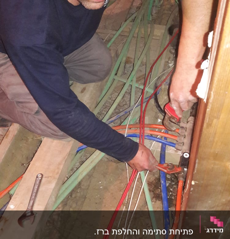 אדם עובד עם מפתח צינורות על צינורות צבעוניים